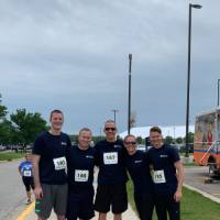 Jeff Stoll standing and smiling with four other GVPD Lakers, wearing their race bibs